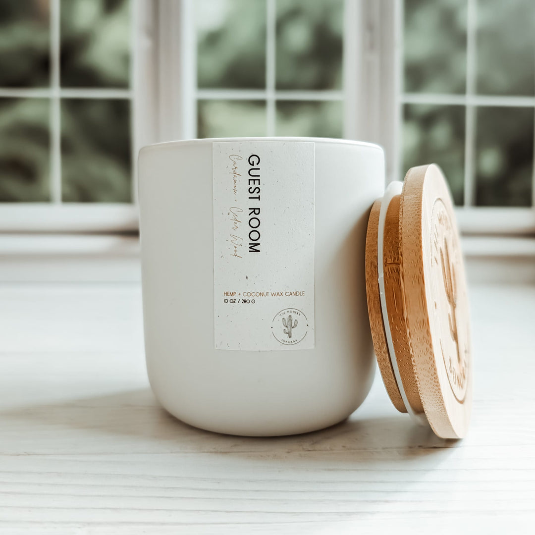 This is the guest room, cardamom and cedarwood scented candle in a soft white colored ceramic jar. It is part of the Modern Farmhouse Collection, a collection of candles designed for the farmhouse decor aesthetic. It is made from our own, unique Hemp & Coconut Wax. It is both soy free and paraffin free - non-toxic, sustainable, & clean ingredient. No Carcinogens, no mutagens, no hormone disruptors, organ toxins, ect. Literally the best candle ever!
