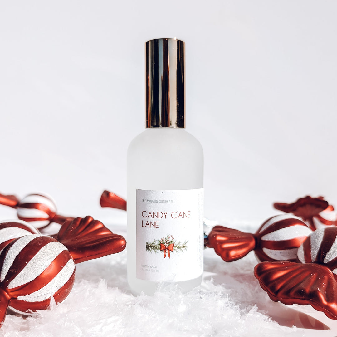 Bottle of 'Candy Cane Lane' perfume with candy canes on a white background