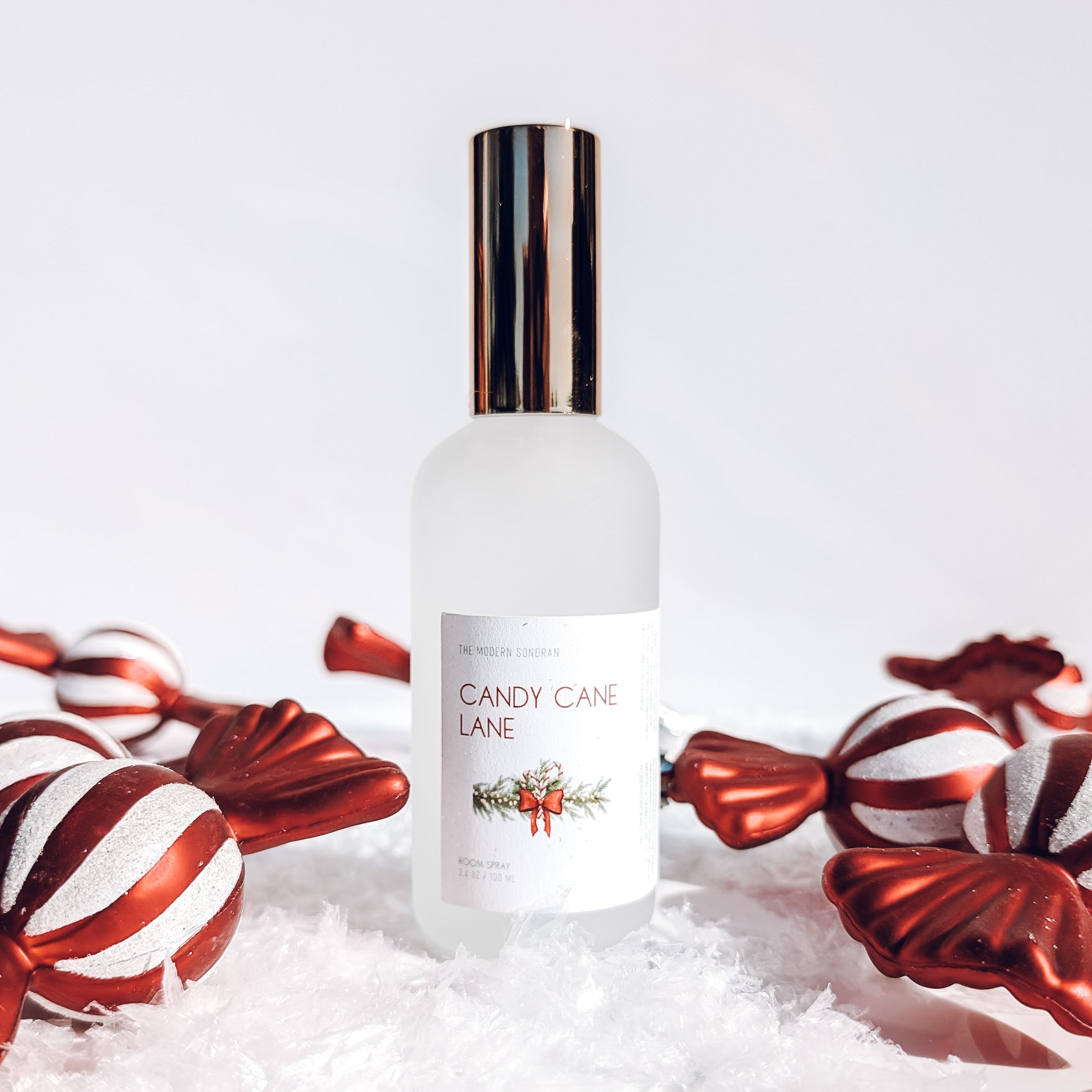 Bottle of 'Candy Cane Lane' perfume with candy canes on a white background