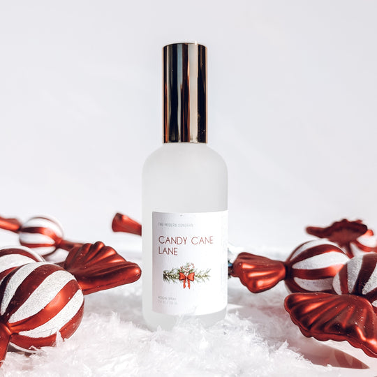 Bottle of 'Candy Cane Lane' perfume with candy canes on a white background