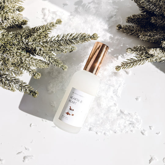 White bottle with gold cap on a snowy surface with pine branches