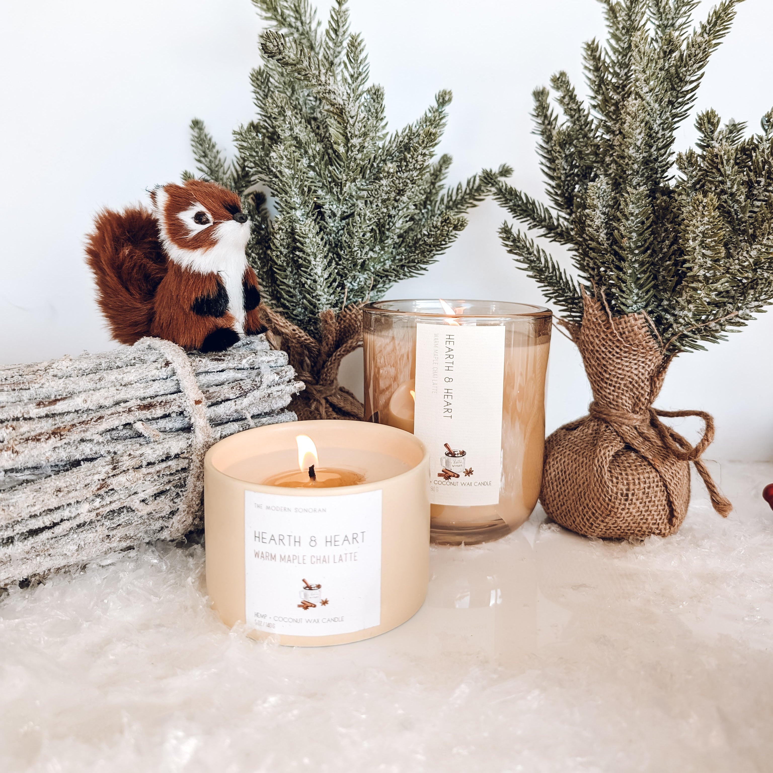 Candle with a label, small tree, and decorative elements on a white surface