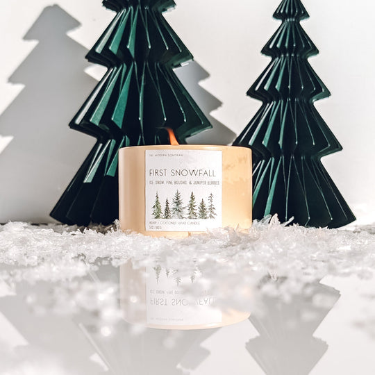 Winter candle with decorative trees on a snowy background