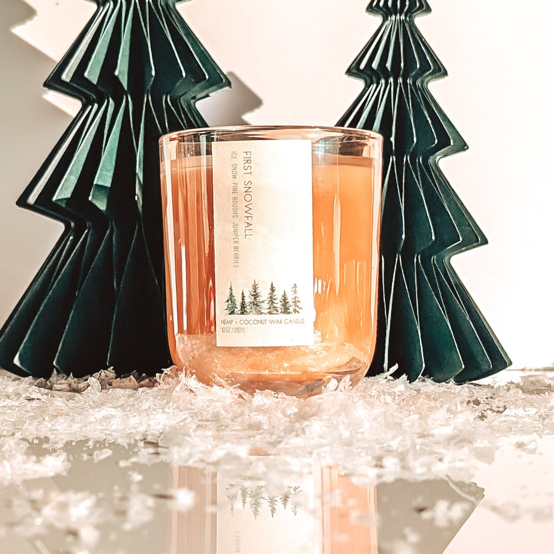 Candle with decorative trees on a reflective surface