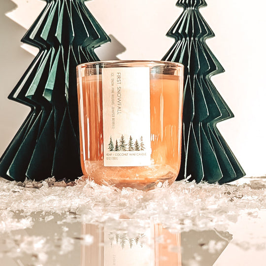 Candle with decorative trees on a reflective surface