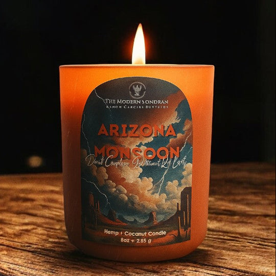 Best-selling Arizona Monsoon Candle set on a rustic wood table with a black background. The arizona monsoon candle is lit, filling the space with the scent of desert creosote and rain drenched sonoran desert earth.