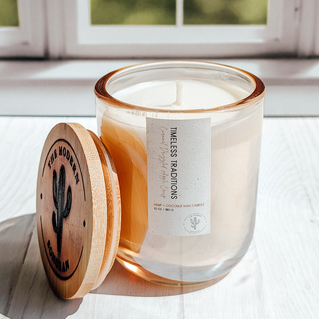 A super cool picture of a glass Timeless Traditions candle in a windowsill ( is windowsil spelled with 2 l's or one?)