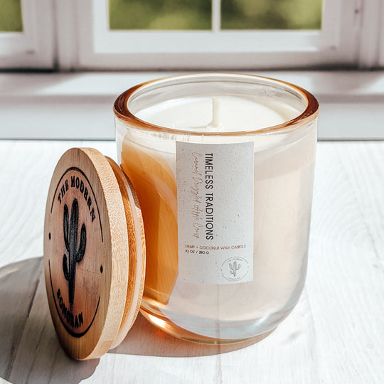 A super cool picture of a glass Timeless Traditions candle in a windowsill ( is windowsil spelled with 2 l's or one?)