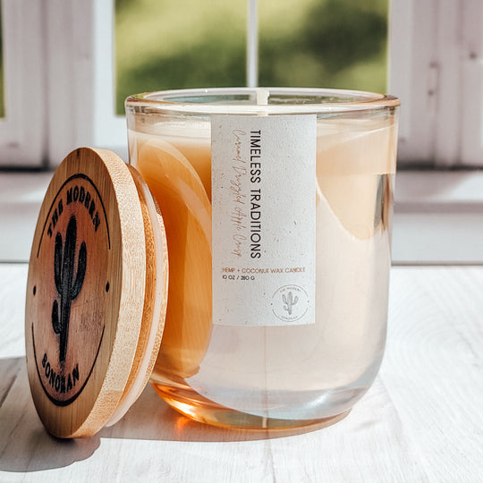 A close up shot of A timeless Traditions candle in a glass jar on a windowsill
