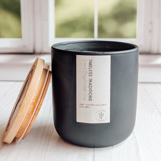 yet another close up shot of a Timeless Traditions candle in a black ceramic jar on a windowsill.