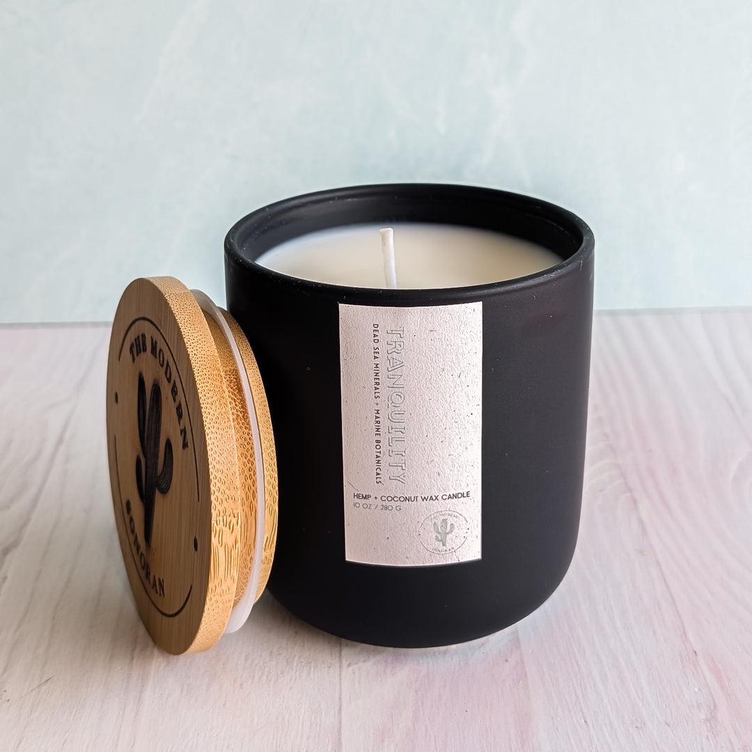 A Tranquility candle in a black jar on a table
