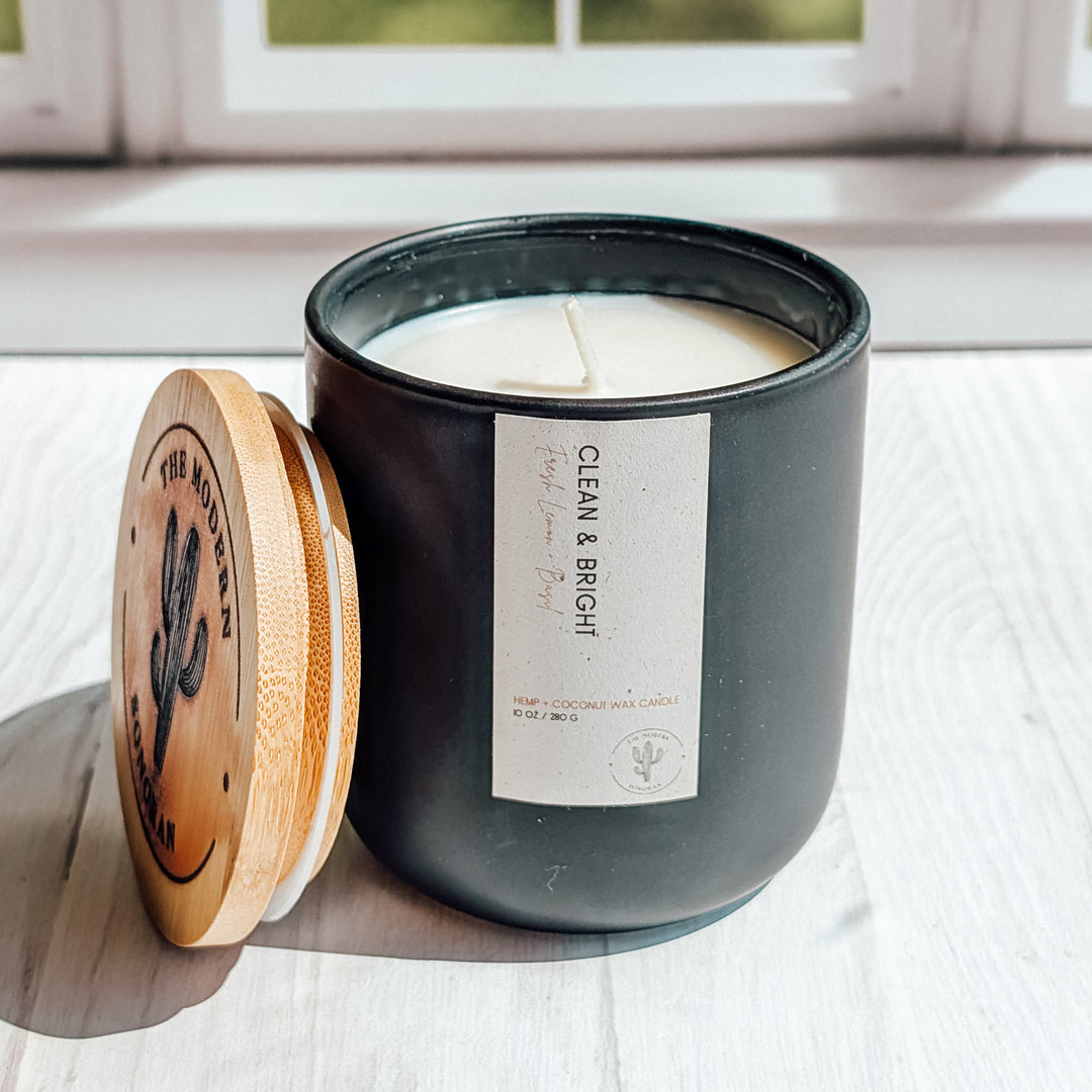 an EXTREME close up shot of a Clean and Bright candle in a black ceramic jar on a windowsill
