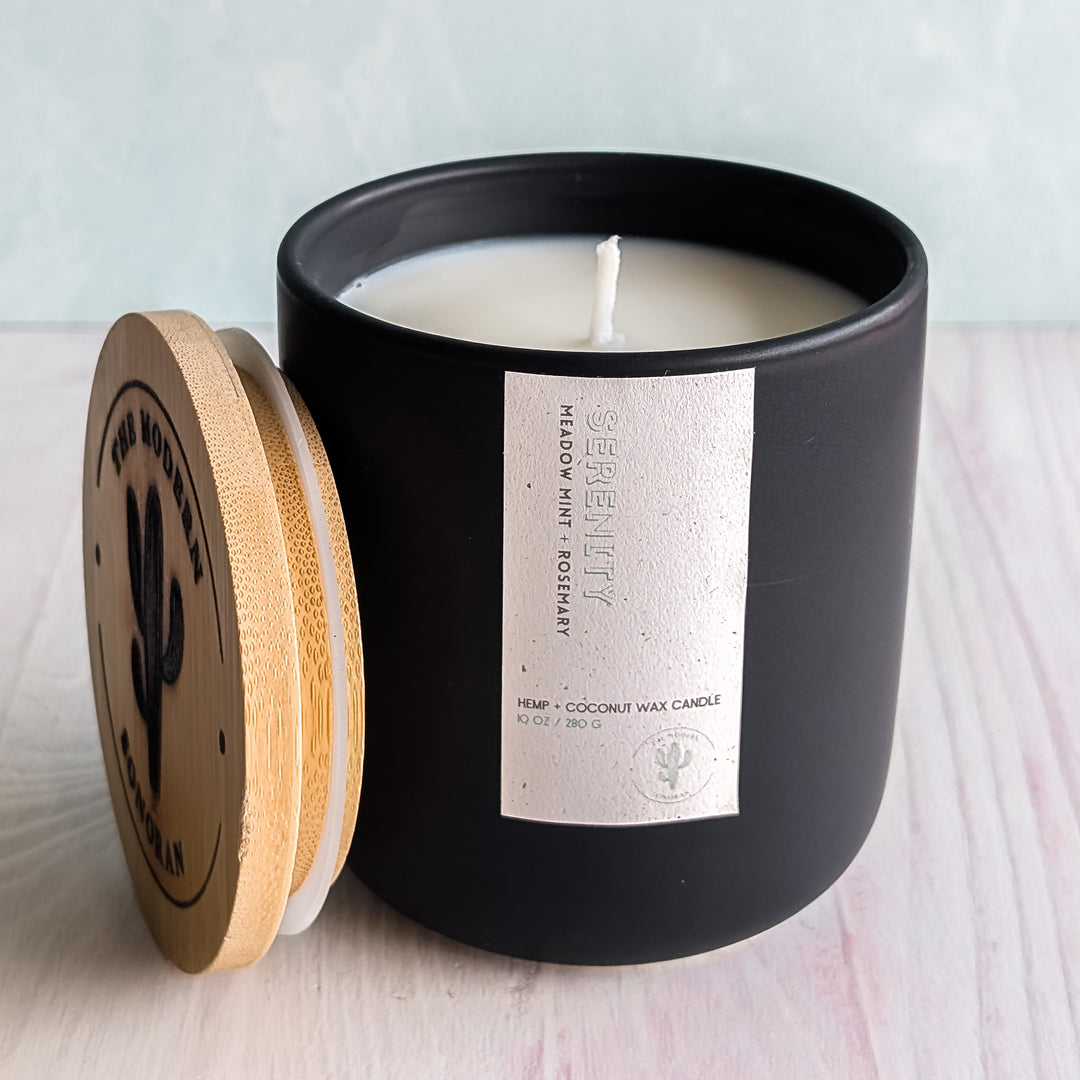 A cool Serenity Candle in a black jar with a boring empty but very clean background