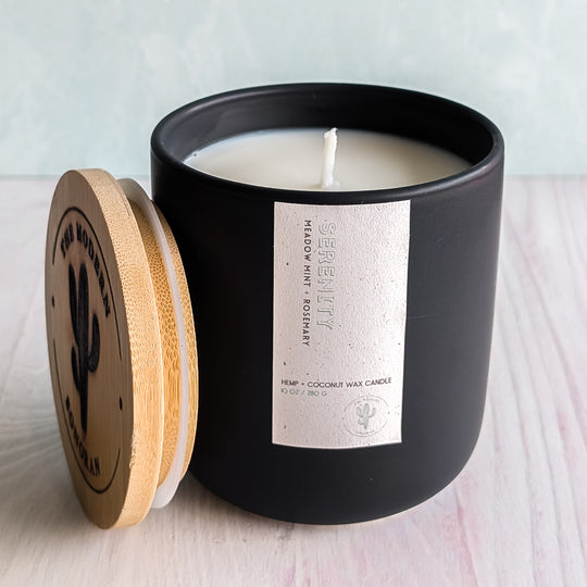 A cool Serenity Candle in a black jar with a boring empty but very clean background