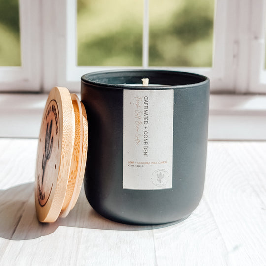 an EXTREME close up shot of a Caffinated and Confident candle in a black ceramic jar on a windowsill